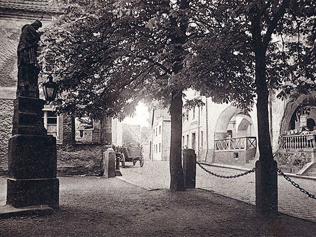 zdjęcie na którym widać kawałek rynku, pierzei i pomnik przy kościele